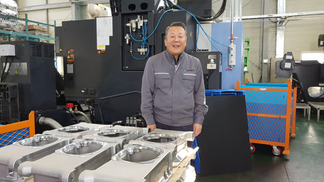 박성기 유진금속공업㈜ 대표이사가 지난 11일 김해시 주촌면 골든루트로 소재 공장에서 만든 진공펌프 부품 앞에서 활짝 웃고 있다.