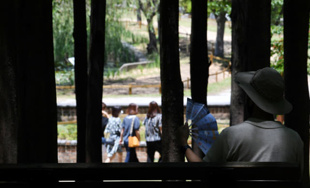 16일 오후 창원대학교 기숙사 앞 편백숲에서 한 시민이 나무그늘 아래 벤치에서 부채질을 하며 더위를 식히고 있다./성승건 기자/