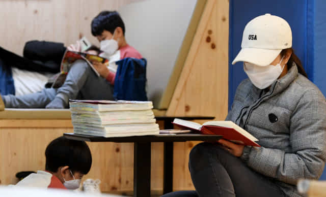 창원시 마산회원구 지혜의 바다 도서관을 찾은 한 가족이 마스크를 착용한 채 독서를 즐기고 있다./경남신문 자료사진/