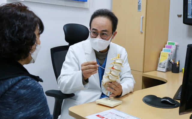 반성배 창원the큰병원 대표원장이 환자에게 척추압박골절에 대해 설명하고 있다. 아래 사진은 척추체성형술로 골절된 뼈에 골시멘트를 주입하는 시술영상.