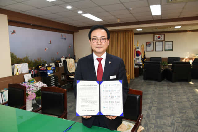 한정우 군수가 14개 지방자치단체 공동건의문에 서명하고 사진을 촬영하고 있다.