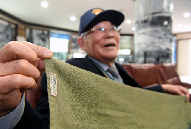류승석씨가 70여년 전 미군 부대에서 받은 국방색 수건을 들어보이고 있다.