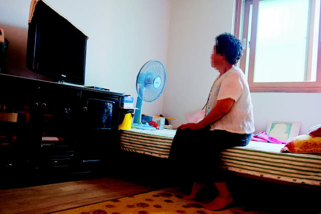 회원동의 한 달동네에 거주하는 송 할머니가 오래된 선풍기로 더위를 식히고 있다.
