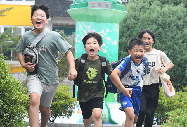 의령 궁류초 신광재(왼쪽부터), 전종인, 이길호, 남예슬 학생이 여름방학 방과후 학교와 돌봄교실을 마친 후 손을 잡고 교정을 달리고 있다.