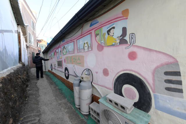 창원시 마산합포구 추산동 가고파 꼬부랑길 벽화마을을 찾은 한 시민이 벽화가 그려진 골목을 걷고 있다.
