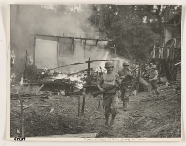 〈사진2〉 인천상륙작전이 감행된 1950년 9월 15일 월미도에서 유엔군 병사들이 소총을 들고 불타고 있는 한 민가 옆을 지나가고 있다./미국 국립문서기록관리청 NARA 발굴·전갑생 제공/