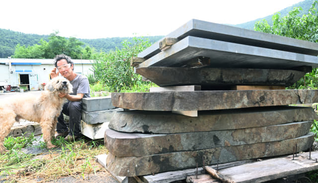 박 조각가가 대리석이 쌓여 있는 작업실 마당에서 반려견 ‘김씨’와 앉아 있다.