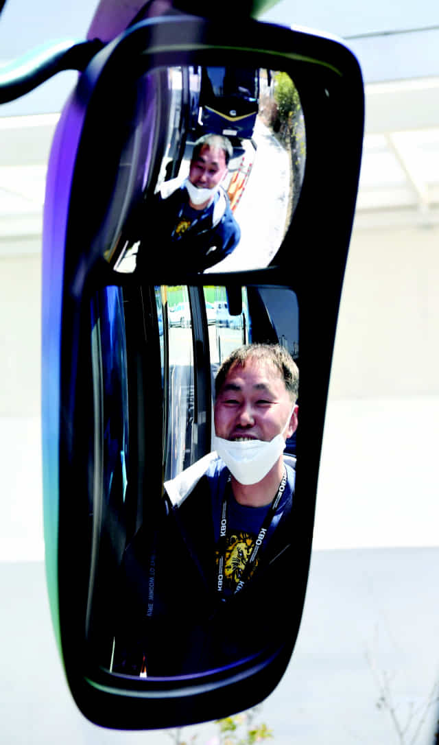 안석환 매니저가 구단 버스 앞에서 환한 미소를 짓고 있다.