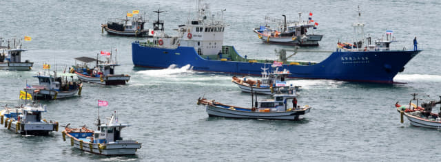 26일 오전 통영시 정량동 이순신공원 앞 해상에서 일본 정부의 후쿠시마 원전 오염수 방류를 규탄하는 해상시위를 하고 있는 어선들 사이로 일본산 활어를 실은 일본배가 동호항으로 입항하고 있다./성승건 기자/