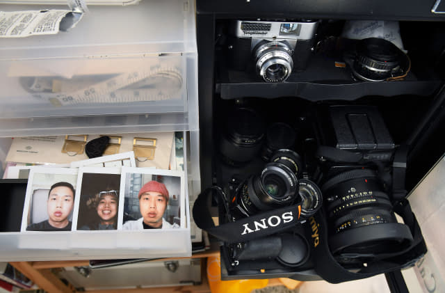 장건율 화가가 폴라로이드 카메라로 촬영한 셀프 포트레이트와 다양한 카메라 장비들이 카메라 제습기에 보관되어 있다.